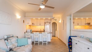 A compact kitchen with white cabinets, a central island with bar stools, and a ceiling fan. - Exclusive Sea Views Villamar - Big Terrace & Pool (Costa Adeje)