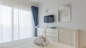 A hotel room with a bed, a television, a mirror, and a window with curtains. - Exclusive Sea Views Villamar - Big Terrace & Pool (Costa Adeje)