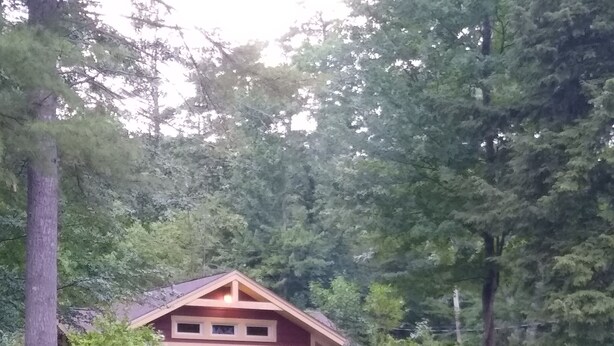 Une maison au bord d’un lac, avec un quai et un bateau.