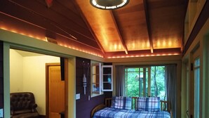 Une pièce confortable avec un lit, une chaise et une petite table. Une fenêtre offre une vue sur la verdure environnante.