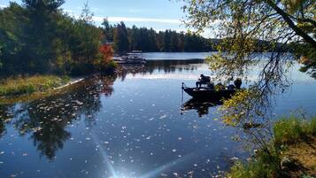 A calm lake with boats, surrounded by trees and vegetation.