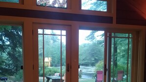 Une pièce spacieuse dotée de grandes portes-fenêtres coulissantes qui donnent sur un jardin avec une table de pique-nique et de la verdure.