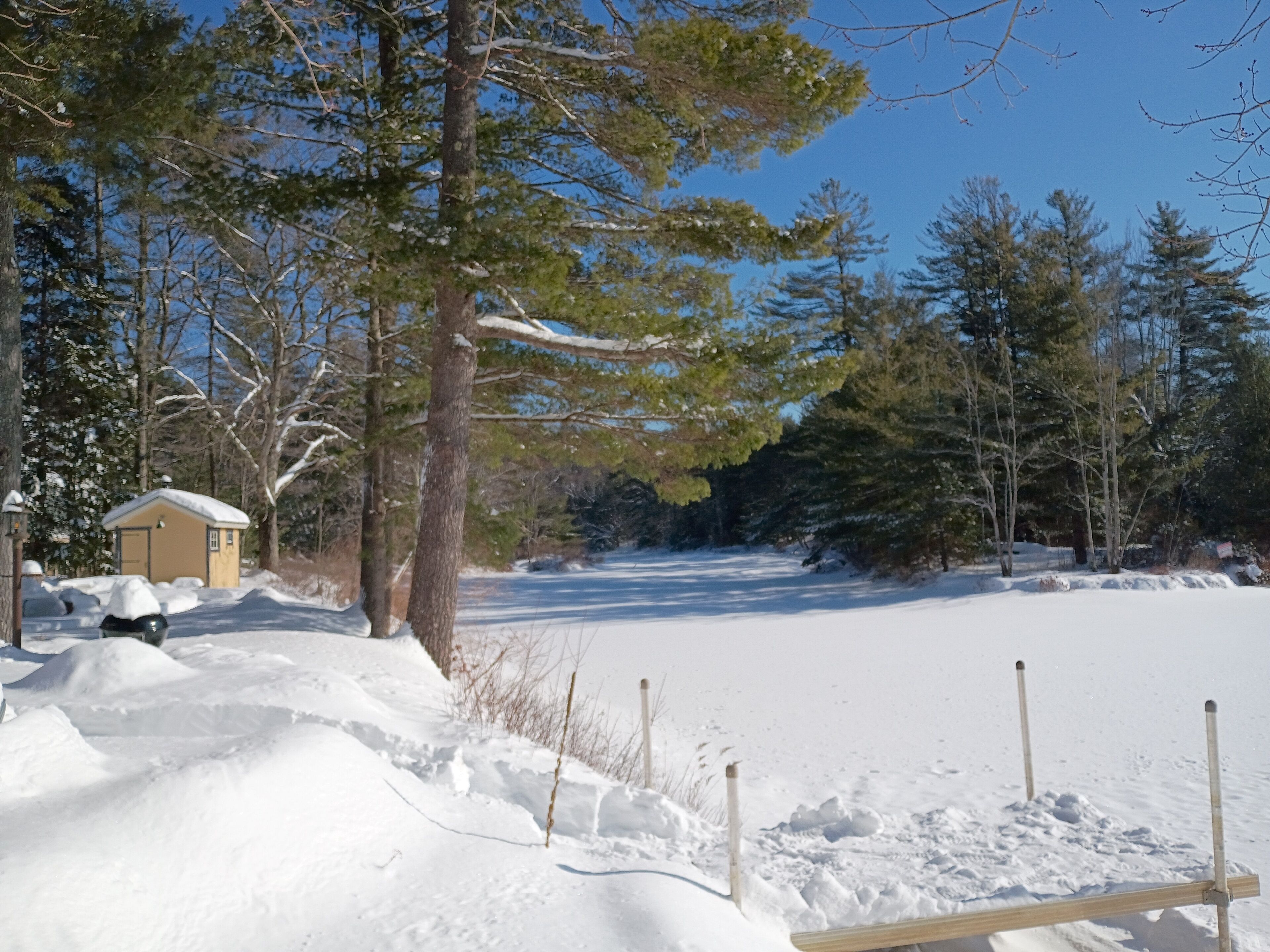 A snowy landscape with a small cabin and a wooden bench.