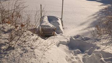 A snow-covered landscape with a wooden bench and a path leading through it.