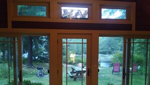 Une pièce dotée de grandes portes-fenêtres coulissantes qui donnent sur un jardin avec une table de pique-nique, des chaises et une balançoire.
