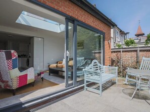 A patio with a glass door leading to a living area, a white bench, and a table. - Super Chic Apartment in Beautiful Sunninghill - Pass the Keys (Sunninghill)