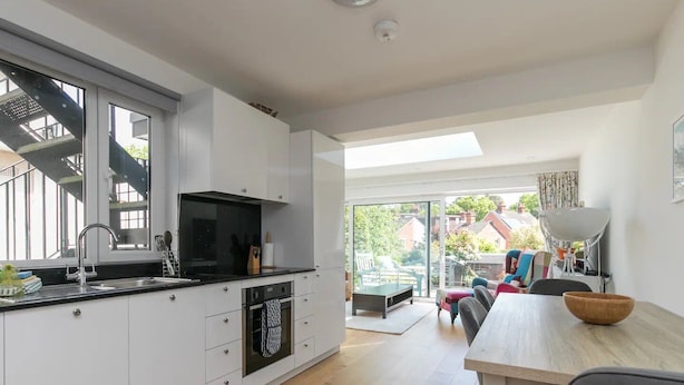 A modern kitchen with white cabinets, a black stove, and a large window. - Super Chic Apartment in Beautiful Sunninghill - Pass the Keys (Sunninghill)