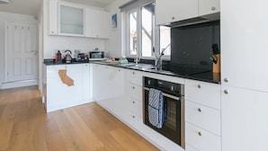 A modern kitchen with white cabinetry, a black countertop, a microwave, a kettle, and a window above the sink. - Super Chic Apartment in Beautiful Sunninghill - Pass the Keys (Sunninghill)