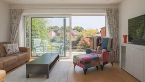 A modern living room with a sofa, a coffee table, a colorful armchair, and a television. - Super Chic Apartment in Beautiful Sunninghill - Pass the Keys (Sunninghill)