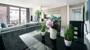 A modern living room with a glass coffee table, grey sofa, and potted plants. - Historical West Belfast | 5 Mins to City Centre - Pass the Keys (Belfast)