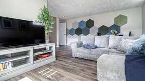 A modern living room with a flat-screen TV, a grey sofa, and a white entertainment unit. - Historical West Belfast | 5 Mins to City Centre - Pass the Keys (Belfast)
