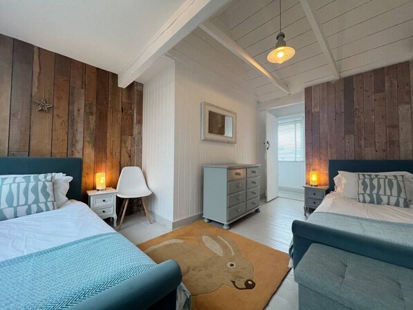 Une chambre avec deux lits, une commode, une chaise et un tapis.