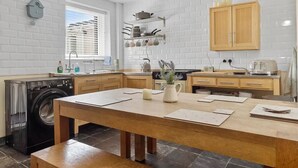 A modern kitchen with a central island, built-in appliances, and a window with blinds.