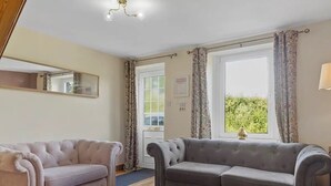 A living room with two sofas, a mirror, and a window with curtains.
