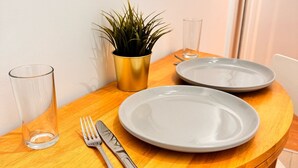 A wooden dining table with two plates, a glass, and a fork. - Cosy Apartment in Canary Wharf  (London)