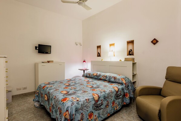 A bedroom with a bed, a chair, a TV, and a desk. - Coralie House (Giardini Naxos)