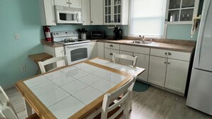 A compact kitchen with white cabinets, a microwave, stove, sink, and a dining table with chairs. - Beach Block! 1 bedroom condo!Perfect for 2 people.Must be 25 years old to stay. (Seaside Heights)