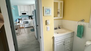 A compact kitchen with white cabinets and a microwave, a bathroom with a sink and toilet, and a dining area with a table and chairs. - Beach Block! 1 bedroom condo!Perfect for 2 people.Must be 25 years old to stay. (Seaside Heights)