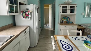 A kitchen with white cabinets, a refrigerator, and a dining table with a blue and white pattern. - Beach Block! 1 bedroom condo!Perfect for 2 people.Must be 25 years old to stay. (Seaside Heights)