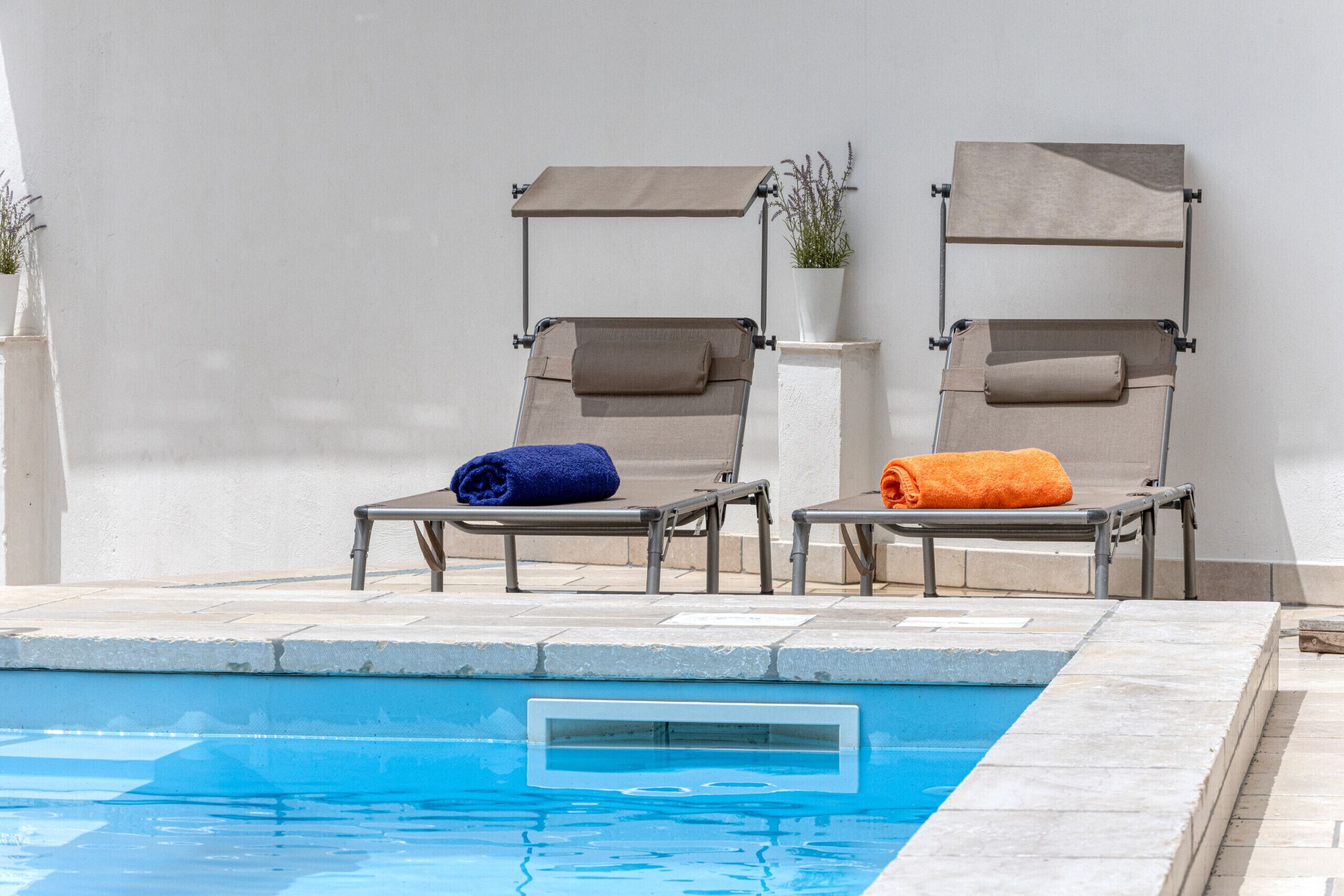 A poolside area with two lounge chairs, each with a towel.