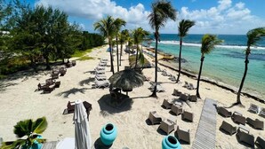 A beach resort with sun loungers, palm trees, and a thatched hut. - Sea view studio with water tank (Saint-François)