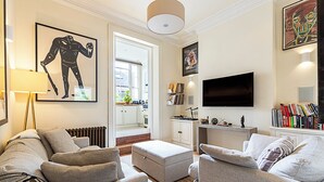 A modern living room with a sofa set, a television, and a bookshelf. - Classic Luxury in Central London (London)