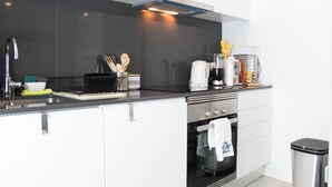 A modern kitchen with a stainless steel sink, a built-in oven, and a coffee maker. - Blossom Cozy Home (Ponta Delgada)