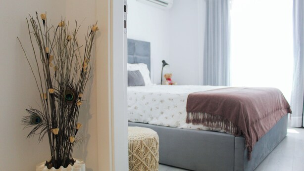 A bedroom with a bed, a macrame pouf, and a decorative vase with branches. - Blossom Cozy Home (Ponta Delgada)