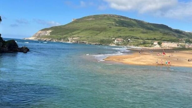 A coastal scene with clear water, a sandy beach, and a hill in the background. - Mikasita: spacious house with mountain views (PV)
