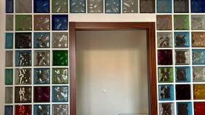 A room with a door leading to another space, surrounded by a wall of colorful glass blocks. - Mikasita: spacious house with mountain views (PV)