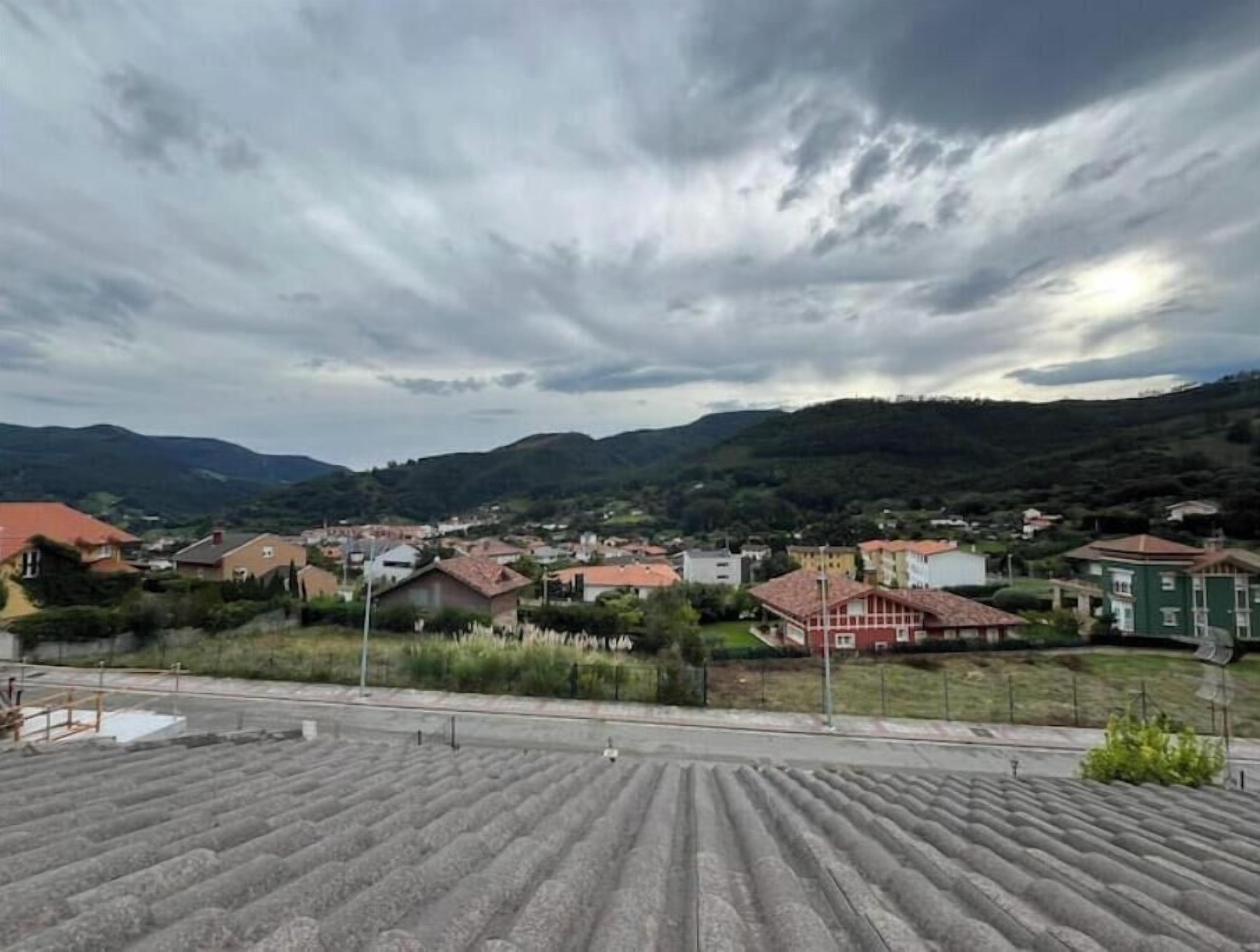 Un quartiere residenziale con case, una strada asfaltata e montagne sullo sfondo.