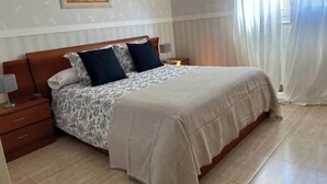 A bedroom with a bed, nightstands, a lamp, a painting, and a window with curtains. - Mikasita: spacious house with mountain views (PV)
