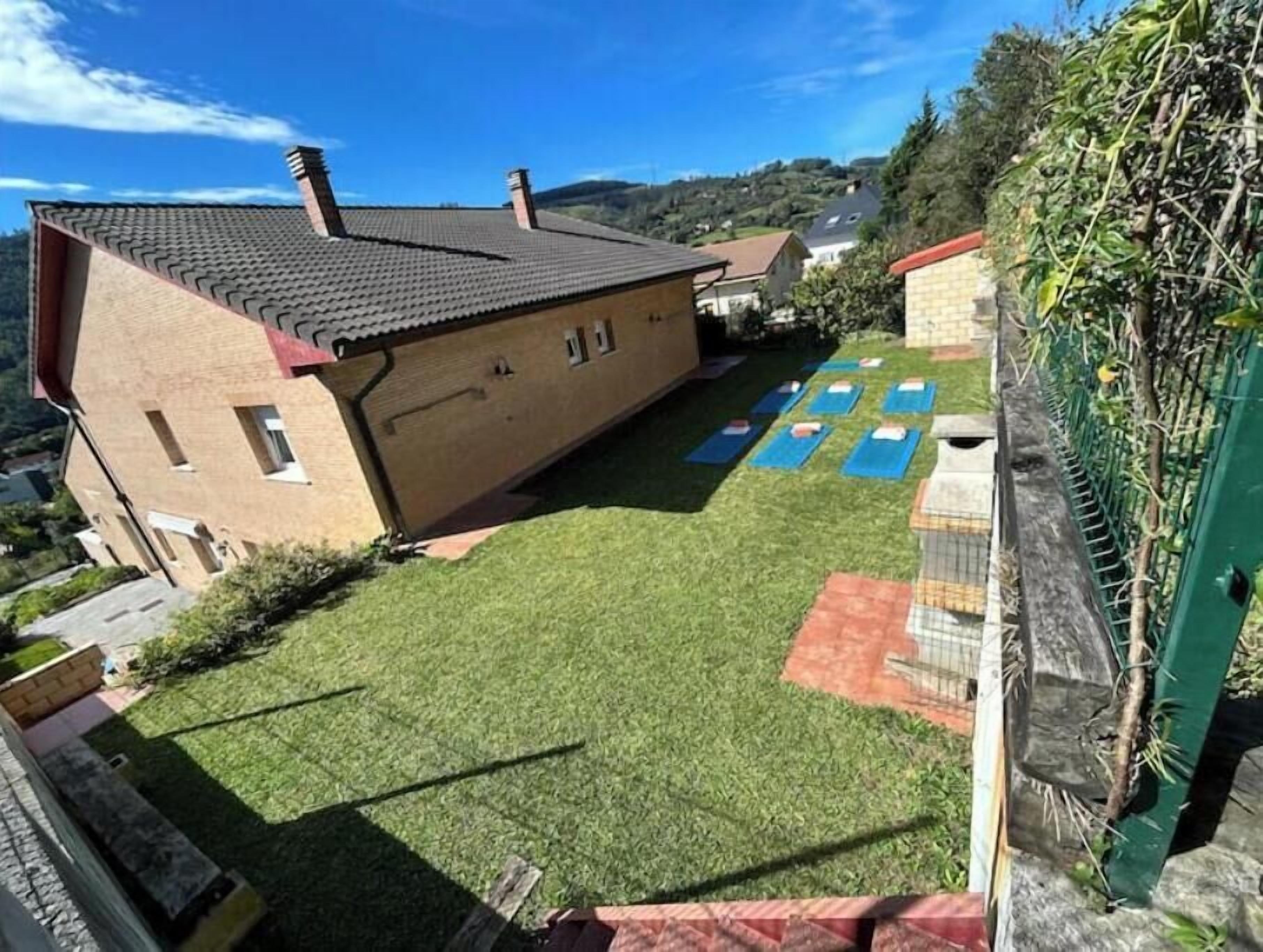 A house with a sloped roof and a fenced yard with exercise mats.