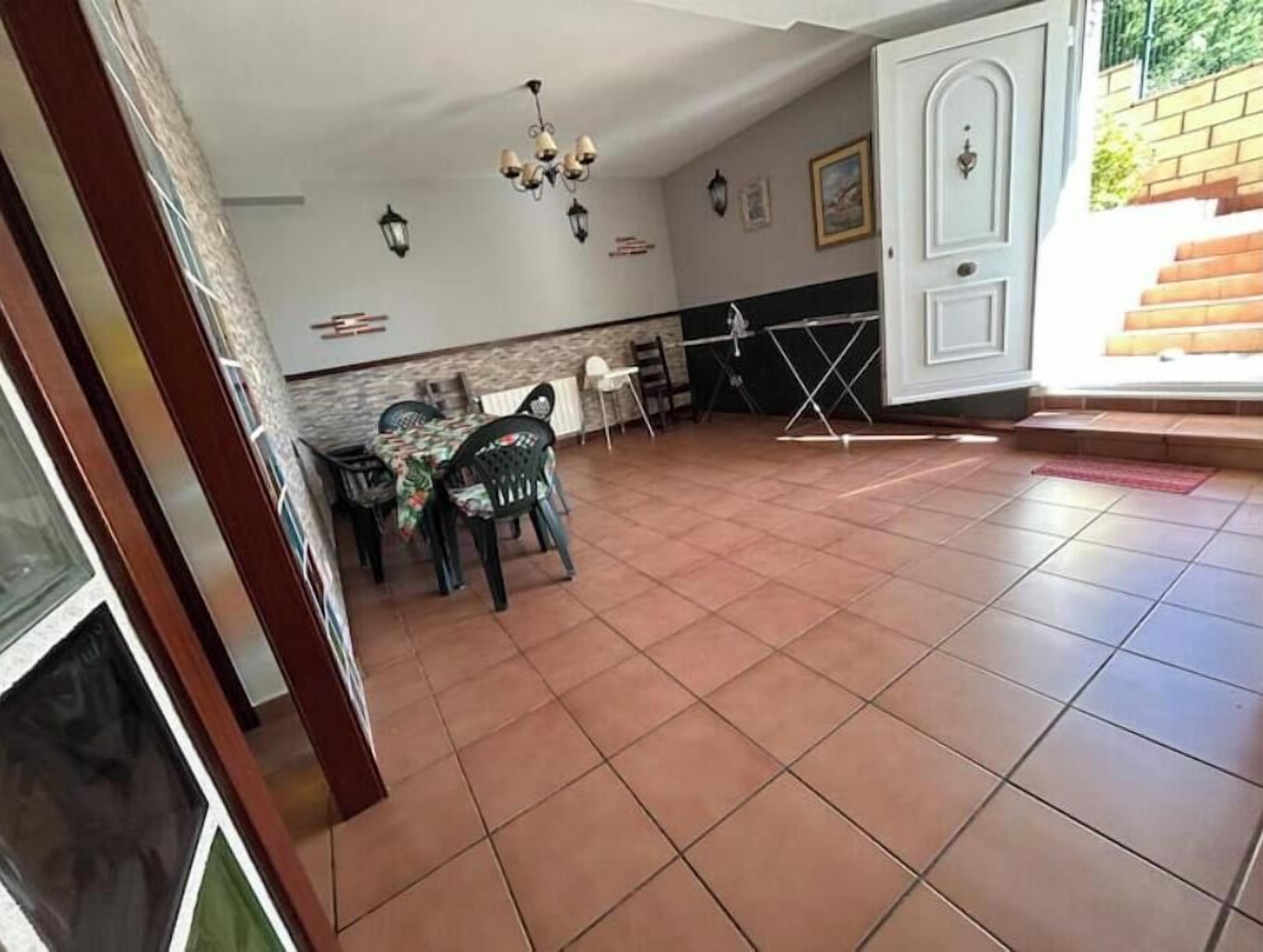Een eetruimte met een tafel, stoelen, een kroonluchter en een deur naar buiten.
