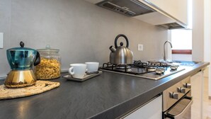 A modern kitchen with a gas stove, kettle, and a jar of cereal. - Antonino 23 - Two Bedroom Apartment, Sleeps 4 (Firenze)