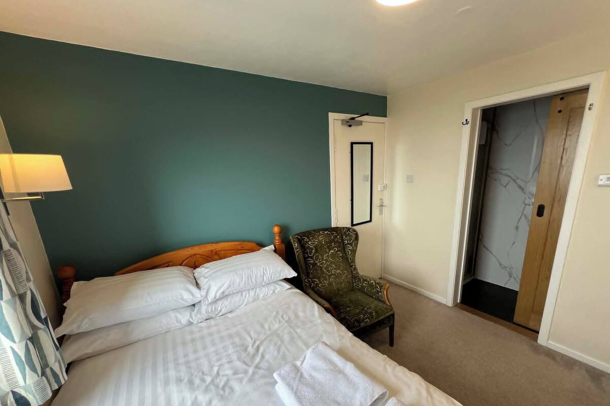 Une chambre d’hôtel avec un lit, une chaise, une porte et une lampe.