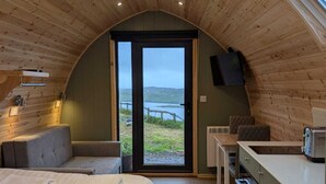 A cozy bedroom with a large bed, a small seating area, and a kitchenette.