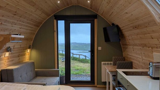 A cozy bedroom with a large bed, a small seating area, and a kitchenette. - Westings Inn (Whiteness)