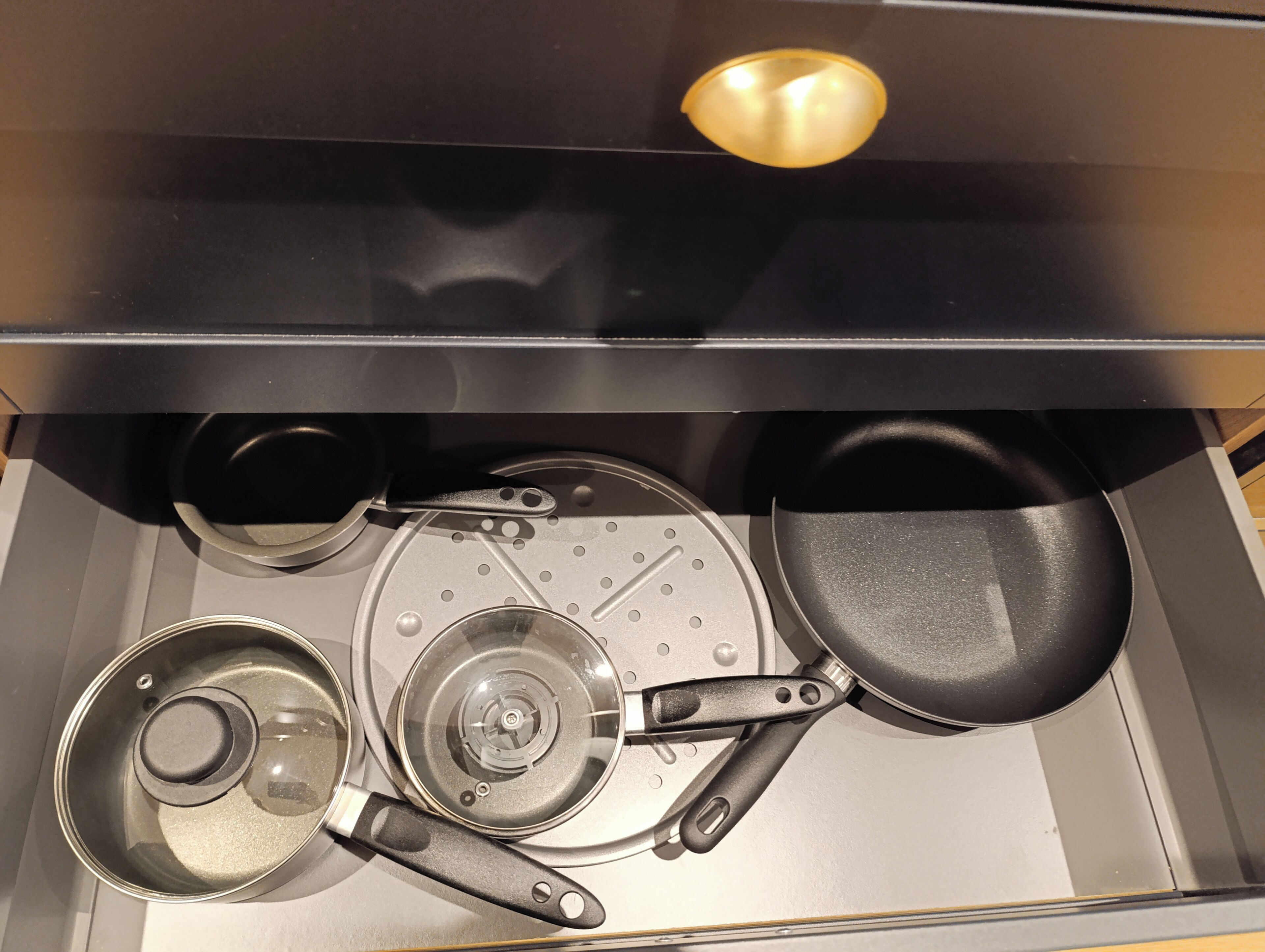 A kitchen with a stove, pots, pans, and a frying pan.