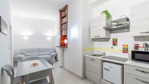 Une cuisine compacte comprenant un coin repas, une bibliothèque intégrée et un petit réfrigérateur.