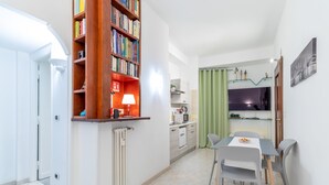 Un espace de vie compact comprenant un coin repas, une kitchenette et une bibliothèque.