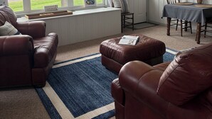 A living room with leather sofas, a dining table, and a view of a lake. - Newly renovated kitchenette. The Cozy cottage at the Marion County Lake. (Marion)