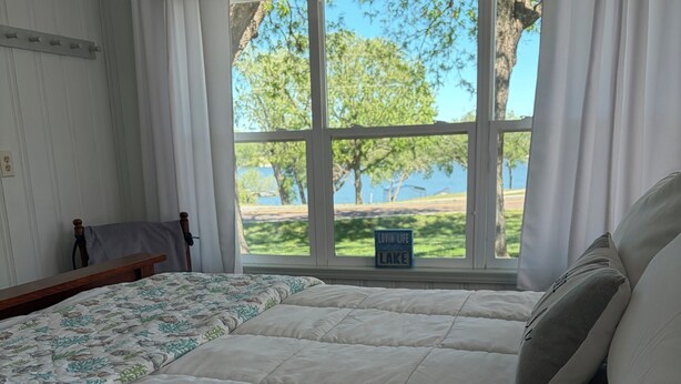 A bedroom with a large bed, a window with curtains, a view of trees and a lake, and a sign reading 'Loving Life Lake'. - Newly renovated kitchenette. The Cozy cottage at the Marion County Lake. (Marion)