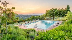 A rectangular swimming pool with a surrounding deck, lounge chairs, and a view of a hilly landscape during sunset. - Villa San Miniato Corniano: Iconic 5 Bedrooms Farmhouse with Pool (San Miniato)