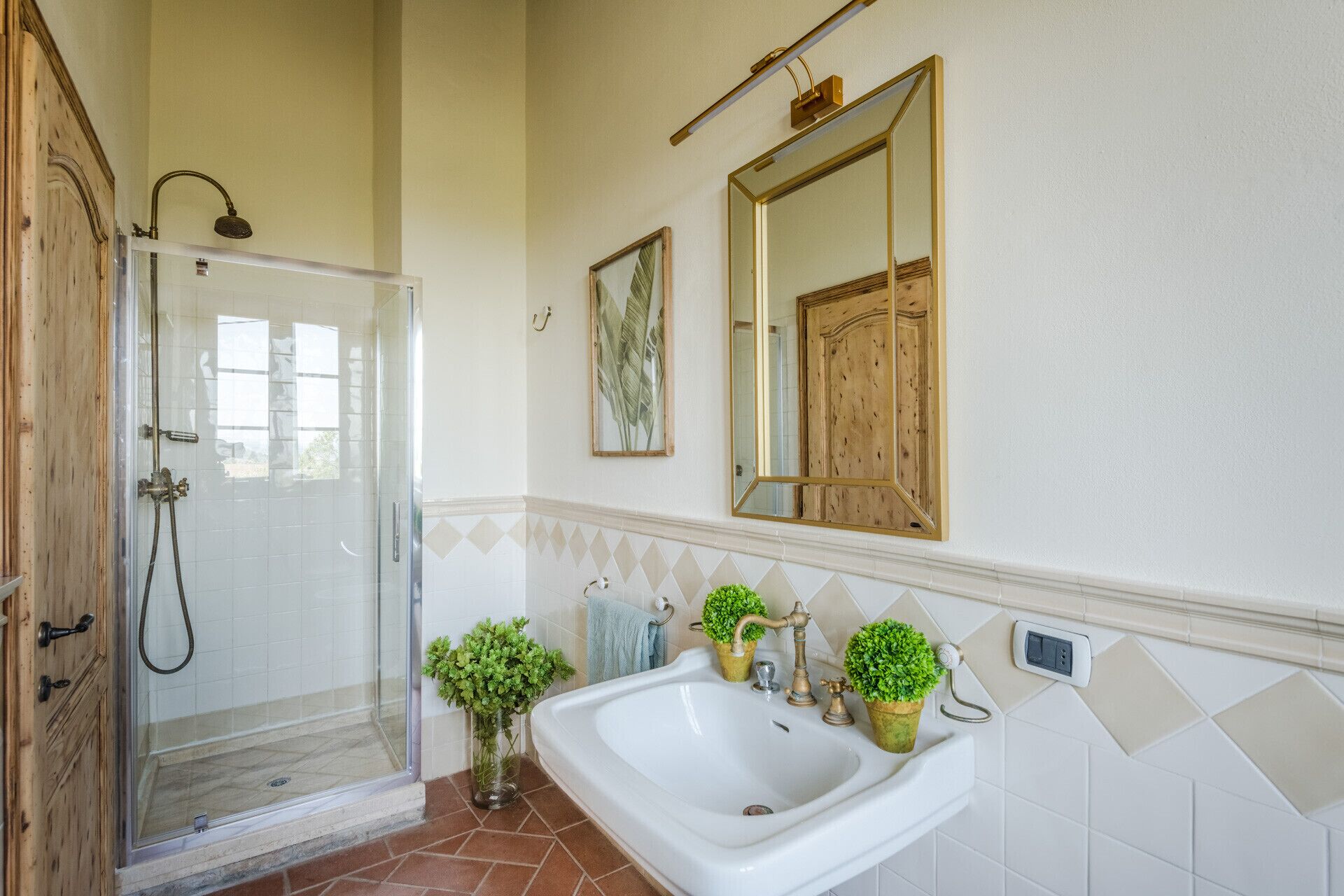 A bathroom with a glass shower enclosure, a white sink with a single faucet, and a mirror above the sink.