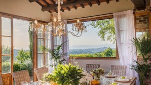 A dining table set with plates, glasses, and a variety of fruits and flowers, overlooking a scenic landscape. - Villa San Miniato Corniano: Iconic 5 Bedrooms Farmhouse with Pool (San Miniato)
