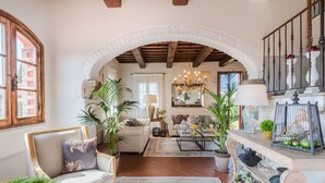 A spacious living room with a high ceiling, exposed wooden beams, a fireplace, and a large arched doorway leading to another room. - Villa San Miniato Corniano: Iconic 5 Bedrooms Farmhouse with Pool (San Miniato)