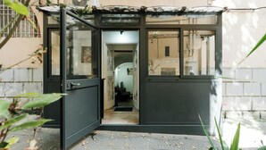 Ein kleiner, abgeschlossener Eingangsbereich mit Glastür, gefliestem Boden und einem sichtbaren Flur, der nach innen führt.