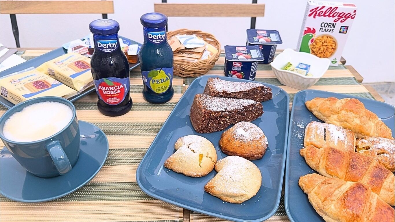 A breakfast table with various food items, including pastries, a coffee cup, and condiments.