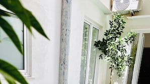 A dining area with wooden tables and chairs, a potted plant, and a window with patterned curtains. - Butera Apartments Luxury (Palermo)